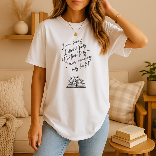 Woman wearing a book lover t shirt featuring handwritten “I am sorry I didn’t pay attention to you. I was reading my book!” text above a floral open-book graphic.