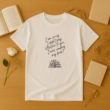 a book lover t shirt featuring handwritten “I am sorry I didn’t pay attention to you. I was reading my book!” text above a floral open-book graphic.
